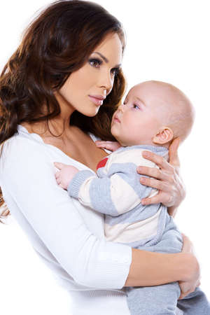 Side view studio portrait of a beautiful young mother cradling her little baby to her chest isolated on whiteの写真素材