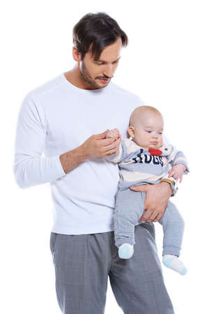Loving father standing holding his small baby on his arm studio portrait isolated on whiteの写真素材
