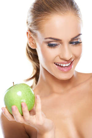 Happy blonde woman with a beautiful smile holding a fresh crisp green apple for a healthy dietの写真素材
