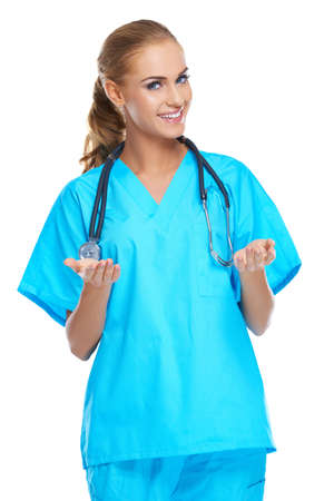 Beautiful confident woman doctor with a lovely friendly smile gesturing with both hands, studio portrait on whiteの写真素材