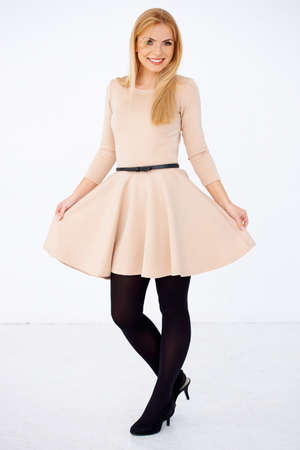 Blond girl in pretty short dress posing and smiling. Isolated on whiteの写真素材