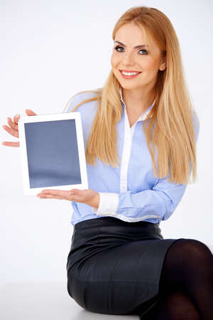 Portrait of blond girl holding a tablet and smiling. White backgroundの写真素材