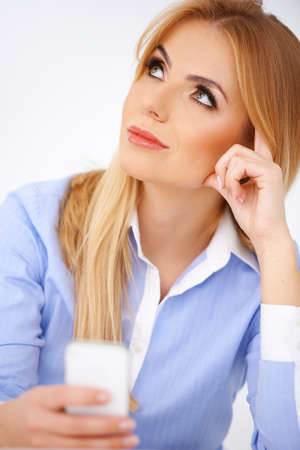 Blond girl holding a cellphone, thinking. White backgroundの写真素材