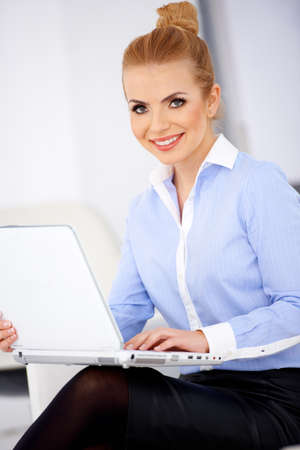 Pretty blond girl and laptop, sitting and smilingの写真素材