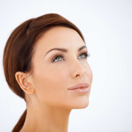 Studio headshot of a beautiful natural serene woman daydreaming looking up into the sky on whiteの写真素材