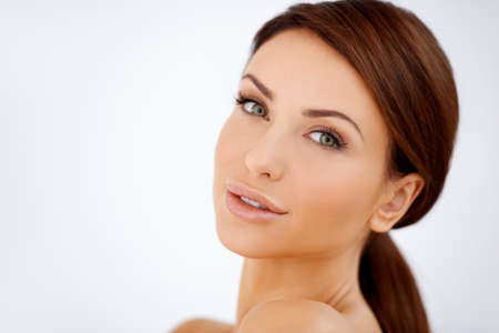 Closeup facial portrait of a beautiful sensual brunette woman with lovely fresh skin isolated on white with copyspaceの写真素材