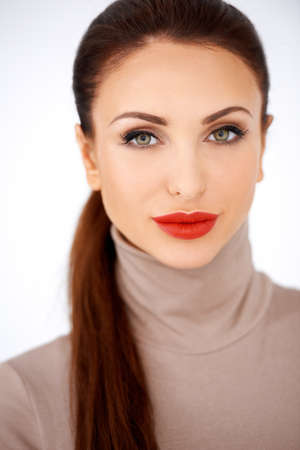 Glamorous elegant woman in red lipstick wearing a stylish polo neck top, head and shoulders frontal portrait isolated on whiteの写真素材