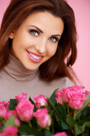 Gorgeous brunette woman with beautiful big eyes holding a bunch of romantic pink rosesの写真素材