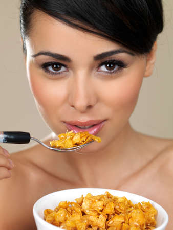 Closeup cropped portrait of a beautiful woman eating a bowl of healthy breakfast cerealの写真素材
