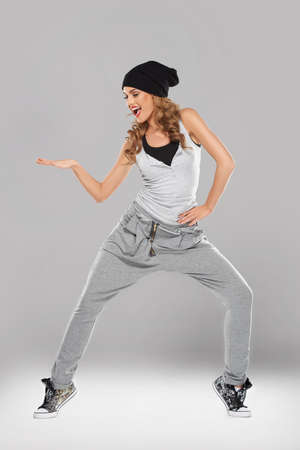 Vivacious beautiful young woman in casual clothes and a black cap singing and striking a poseの写真素材