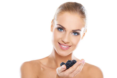 Smiling beautiful healthy woman with a lovely smile holding a handful of fresh blackberriesの写真素材
