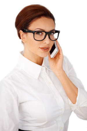 Attractive young brunette businesswoman in heavy framed glasses using a mobile phone isolated on whiteの写真素材