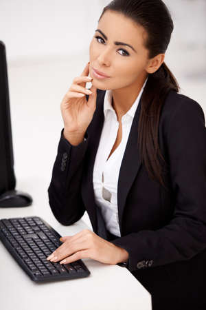 Confident business woman in black suit sitting in front of computerの写真素材