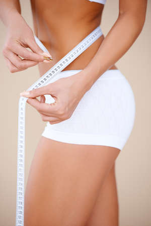 Close up of a neat woman's body part in white shorts  he using masure tapeの写真素材
