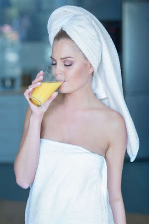 Beautiful woman in towel drinking a healthy glass of juiceの写真素材