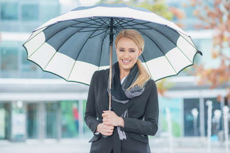 Smiling young woman under an open umbrellaの写真素材