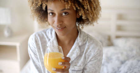 Curly with pleasure girl drinking orange juice