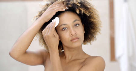 Young woman cleaning face with cotton padの写真素材