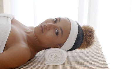 Young beautiful and healthy african american woman in spa salon looking at the cameraの写真素材