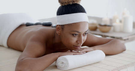 Beautiful ethnic client being treated with hot stone therapy at a luxury health spaの写真素材