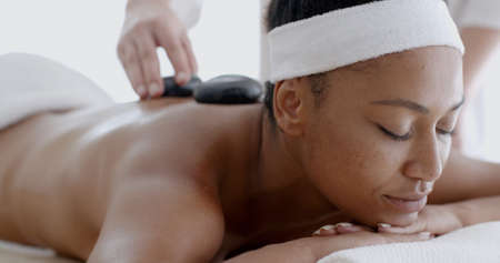 African-american woman receiving a massage with hot stone in a spa center