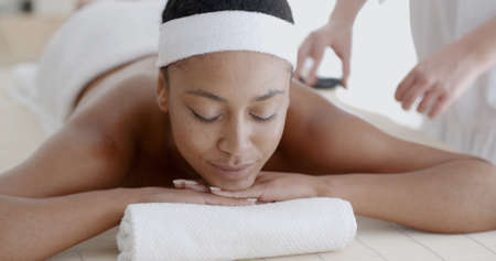 African-American woman relaxing at a health spa while having a hot stone treatment or massageの写真素材