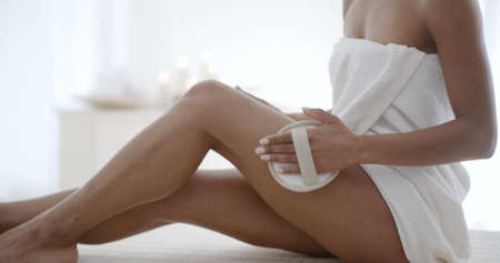 Young woman massaging leg with massage brush in the spa salonの写真素材