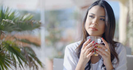 Young woman stirring her hot drink and relaxing in cafe in the city