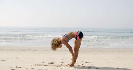 Female athlete doing workout during the morning training on the beach