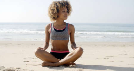 Fit smiling woman sits on the beach