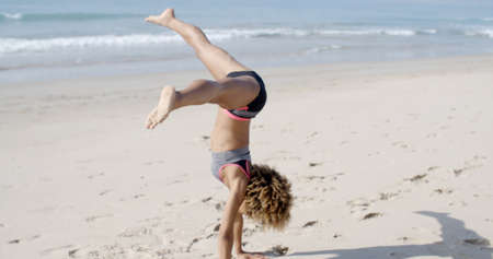Young african american woman doing cartwheel on beach