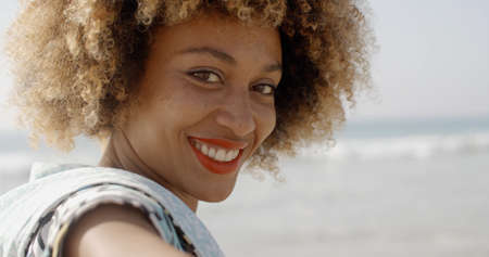 Woman smiling at camera and takes the arm on the beachの写真素材
