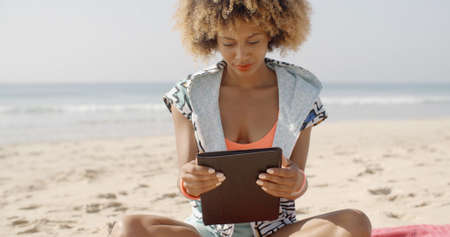 Girl using tablet pc at the beach on a sunny dayの写真素材