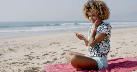 Young woman listening to music on headphones on the beach