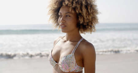 Young african-american woman at the beach on a sunny day looking around.の写真素材