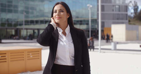 Stylish businesswoman waiting for someone standing in an urban square looking to the side...