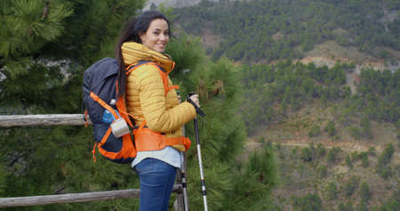 Young woman hiking on a mountain plateau with a backpack and poles in a healthy lifestyle and...