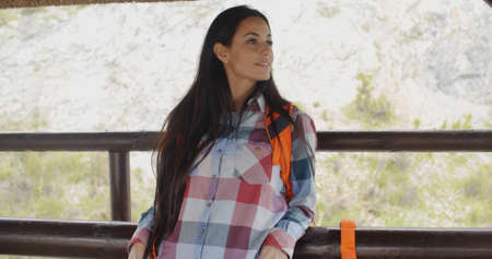 Young attractive woman backpacker standing on a mountain lookout with her rucksack admiring the surrounding sceneryの写真素材