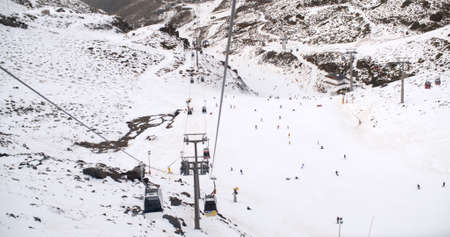 View from a ski lift of skiers below on a run at the ski resort and the mountain valleys stretching away into the distance belowの写真素材