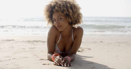 Young woman in a swimsuit relaxing on the sand of the beach in slow motionの写真素材
