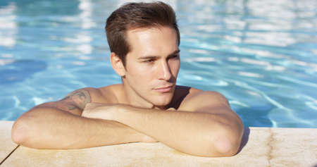 Man stands alone in pool and smiles at camera on a bright summer afternoonの写真素材