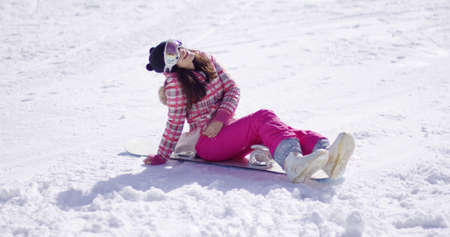Happy young woman sat on snowboardの写真素材