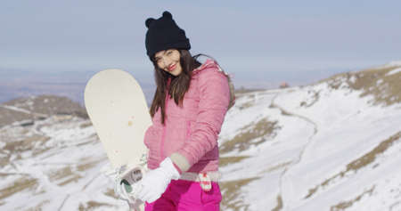 Young woman with snowboard in mountainsの写真素材