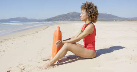 Lifeguard sitting with rescue float on beachの写真素材