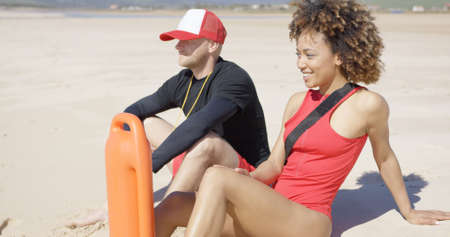 Smiling lifeguards sitting on beach