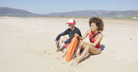 Female and male lifeguards patrolling beachの写真素材