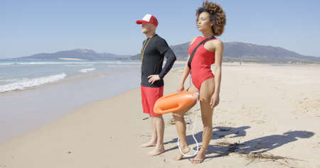 Female and male lifeguards posing on beachの写真素材