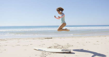 Female listening music and jumping on beachの写真素材
