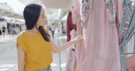 Beautiful young woman in casual outfit walking in mall alone and observing beautiful clothing while shopping alone.の写真素材