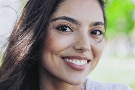 Headshot of wonderful ethnic girl with brown hair smiling at camera in summer sunlight.の写真素材